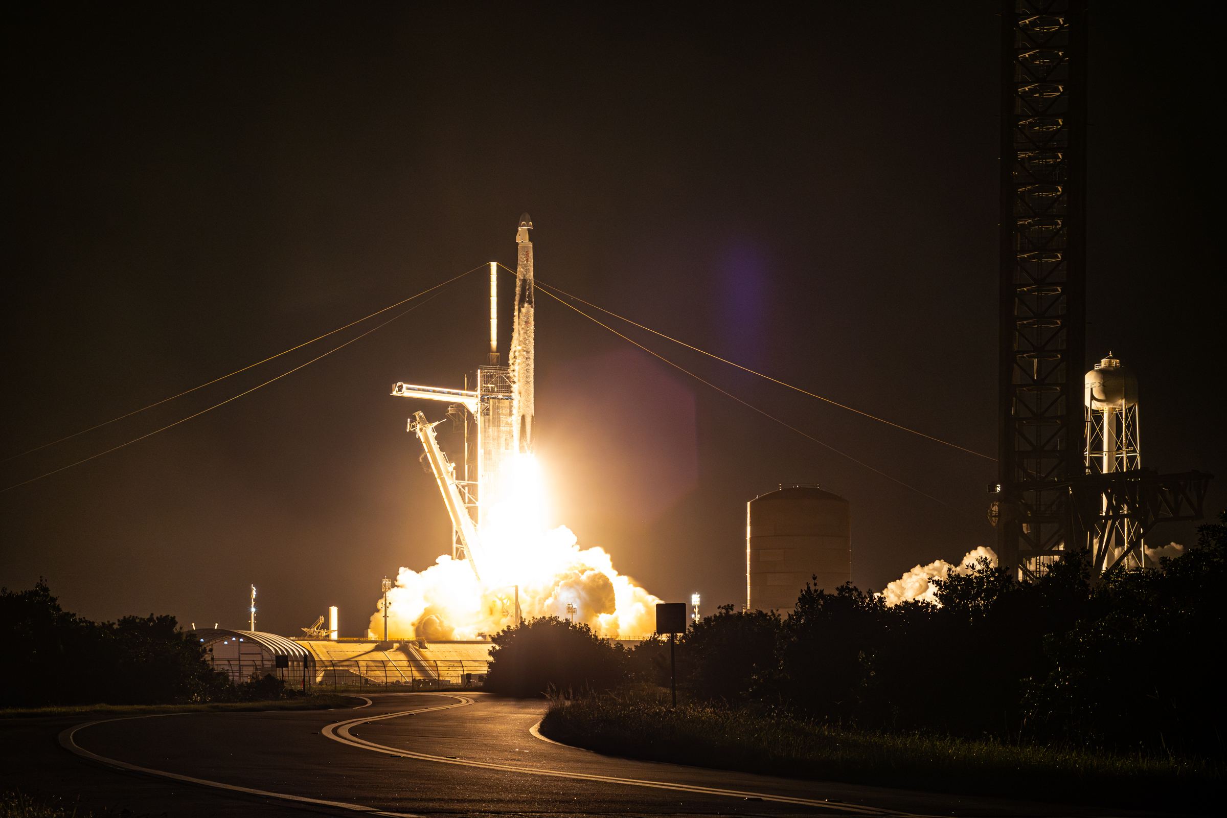 Falcon 9 lifting off from 39A with Crew-7. Transformations for Starship at the pad can be seen, like the tower. It's night, and there is a octagonal lens flare from my 50mm Nikon 1.8D lens in use.