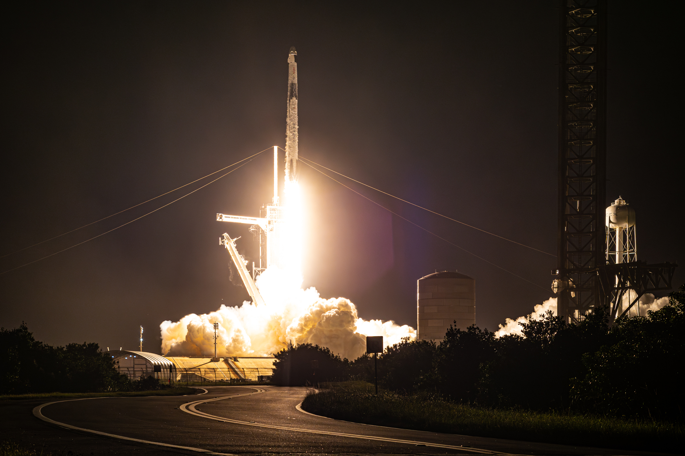 Falcon 9 lifting off from 39A with Crew-7. Transformations for Starship at the pad can be seen, like the tower. It's night, and there is a octagonal lens flare from my 50mm Nikon 1.8D lens in use.