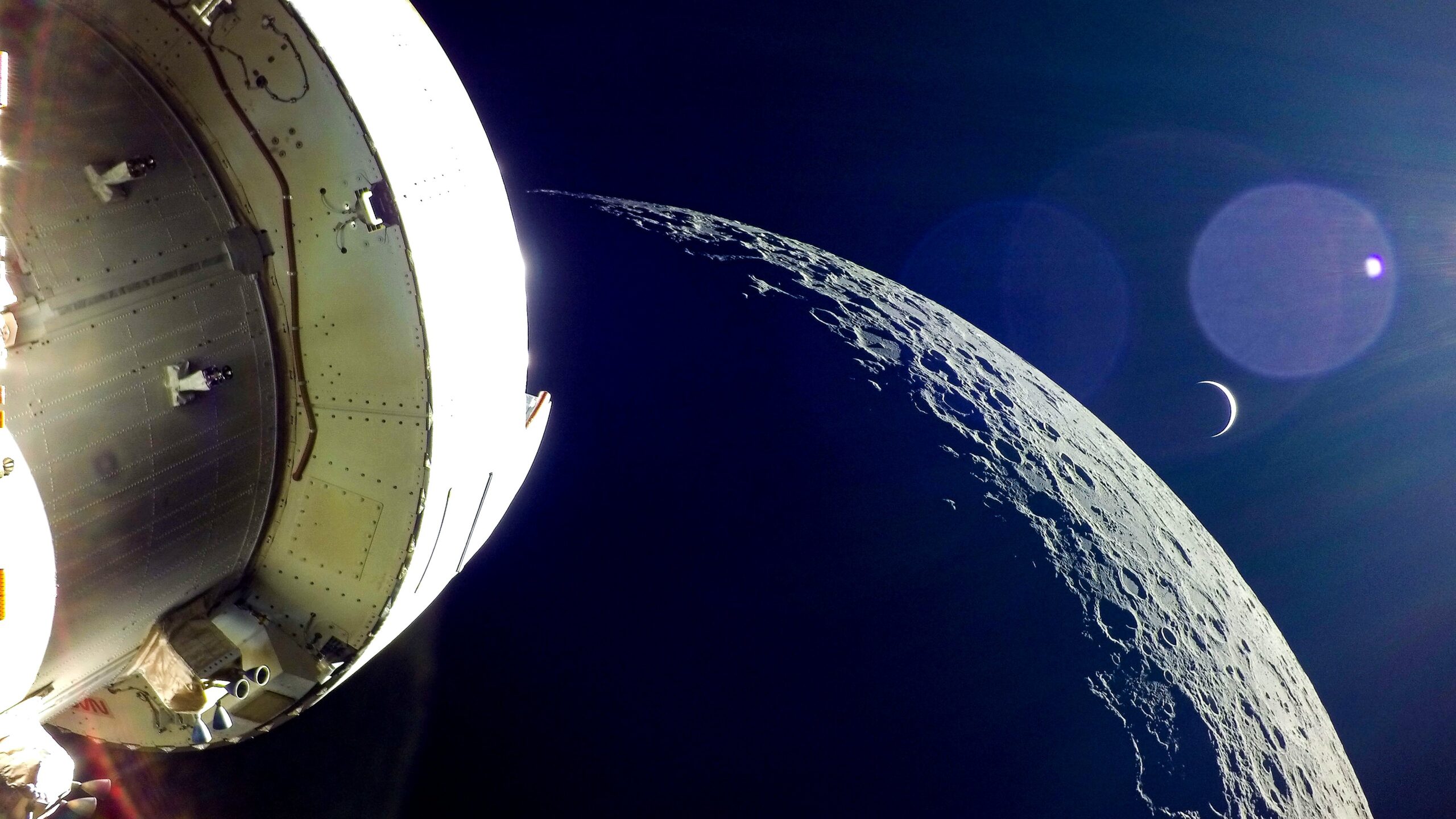 Orion emerges from behind the moon with Earth partially shadowed.